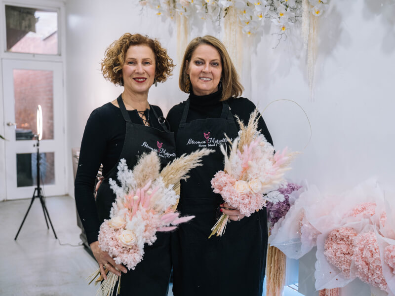 Two women holding bouquets at a floristry class. 